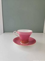 teacup on saucer side view showing pink exterior and gold accents
