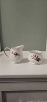 front view of Sadler England cream pitcher and sugar bowl showing floral motif and gold trim