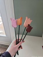 Four wooden tulip stakes held in hand showing colours and overall appearance
