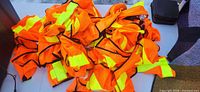 Pile of orange reflective vests on table