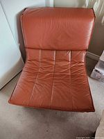 Front view of red leather armless chair showing seat and back panels