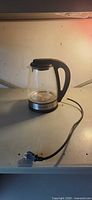 Front view of Hamilton Beach glass electric kettle on base with cord