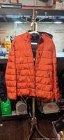 Front view of orange Michael Kors puffer jacket on stand