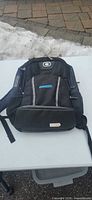Front view of black Ogio backpack showing Andritz logo, exterior pockets, shoulder straps