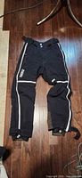 Full view of black Phenix snow pants laid flat showing overall design