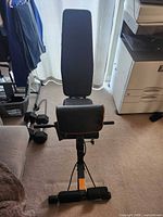 Front view of adjustable weight bench showing backrest, seat, preacher curl pad and leg hold-down bar