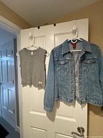 Blue denim jacket and grey sleeveless top on door