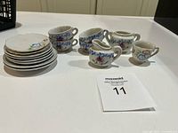 Stacked plates, four teacups, creamer and small pitcher arranged on table