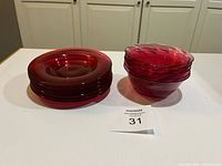 Stack of cranberry glass plates and bowls
