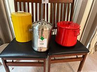 Three items displayed: yellow canister, stainless compost pail, red enamel pot