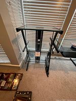 Front view of assembled glass desk showing three shelves and black metal frame