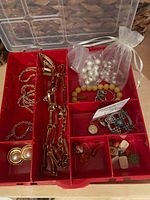 Open red organiser showing assorted jewellery pieces