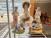 Group view of all seven figurines and dolls on shelf