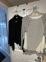 Black cardigan and black-and-white sweater on hanger