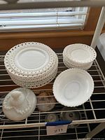 Stacks of lace-edge dinner and salad plates next to serving bowl and lidded piece