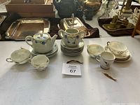 Group shot showing teapot, sugar bowl, five cups and stack of saucers