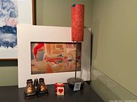 Lot overview showing lamp, abstract print in mat, pair of gold baby shoe bookends, heart box, mini book