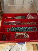Red compartment box open showing assorted jewelry pieces