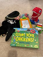 Group shot of board game, pirate costume, dinosaur toy, drawing board, rainbow toy, small pieces