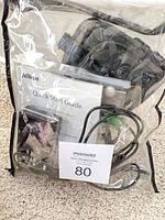 Clear pouch containing Nikon camera body, charger, strap, USB cable, Quick Start Guide