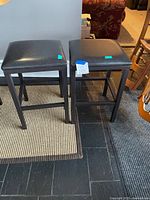 Two black faux leather counter stools front view