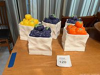 four ceramic canisters with fruit lids on table