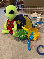All items grouped: plush alien, wall clock, plastic beach toys, storage basket