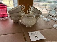 Stacked porcelain cups and matching creamer on table
