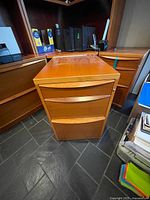 Front view showing three drawers and teak finish