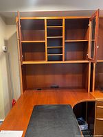 Front view of teak desk and hutch showing shelving and glass door