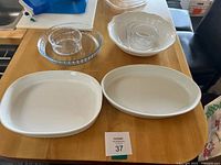 Top view of two white platters, white bowl with nested glass bowls, round glass baking dish with nested bowl