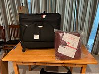 Closed Samsonite suitcase beside sealed Sunbeam blanket on table