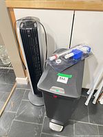 Tower fan and trash can side by side with fill valve kit on top