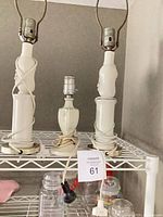 Three porcelain lamp bases on shelf showing size comparison and cords