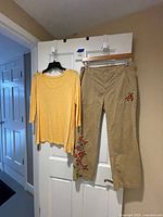 Yellow top and khaki embroidered pants hanging on door