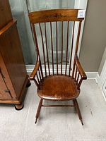 Full view of wooden spindle-back rocking chair showing overall design and wear