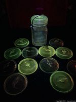 Jar and twelve glass lids glowing under UV light