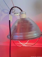 Side view of metal reflector heat lamp emitting red light