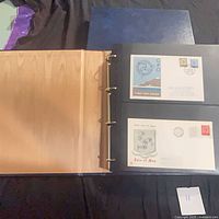 Album open showing two Isle of Man first day covers mounted in plastic sleeves