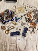 overview of assorted broken costume jewelry spread on fabric background