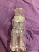 Full view of glass Mr. Peanut jar with lid on purple background