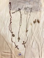 Group shot showing 3 rosaries, cross pendant, figurine, container