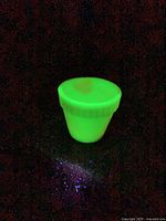 Planter glowing bright green under UV light, showing uranium content