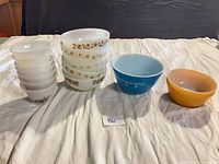 Group shot of all 14 milk glass pieces: stacked custard cups, Termocrisa bowls, blue Pyrex bowl, yellow Fire King bowls