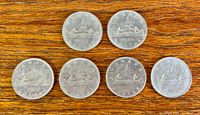 Six 1968 Canada dollar coins on wood surface, all reverse side visible