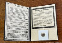 Entire booklet open showing story, certificate, and coin in holder