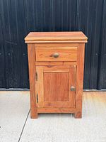 Front view of hardwood bedside cabinet showing drawer, cupboard door and knobs