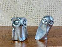 Front view of both aluminum owl figurines