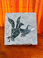Front view of soapstone tile on stand showing carved loon design