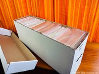 White long box filled with bagged comics, lid alongside